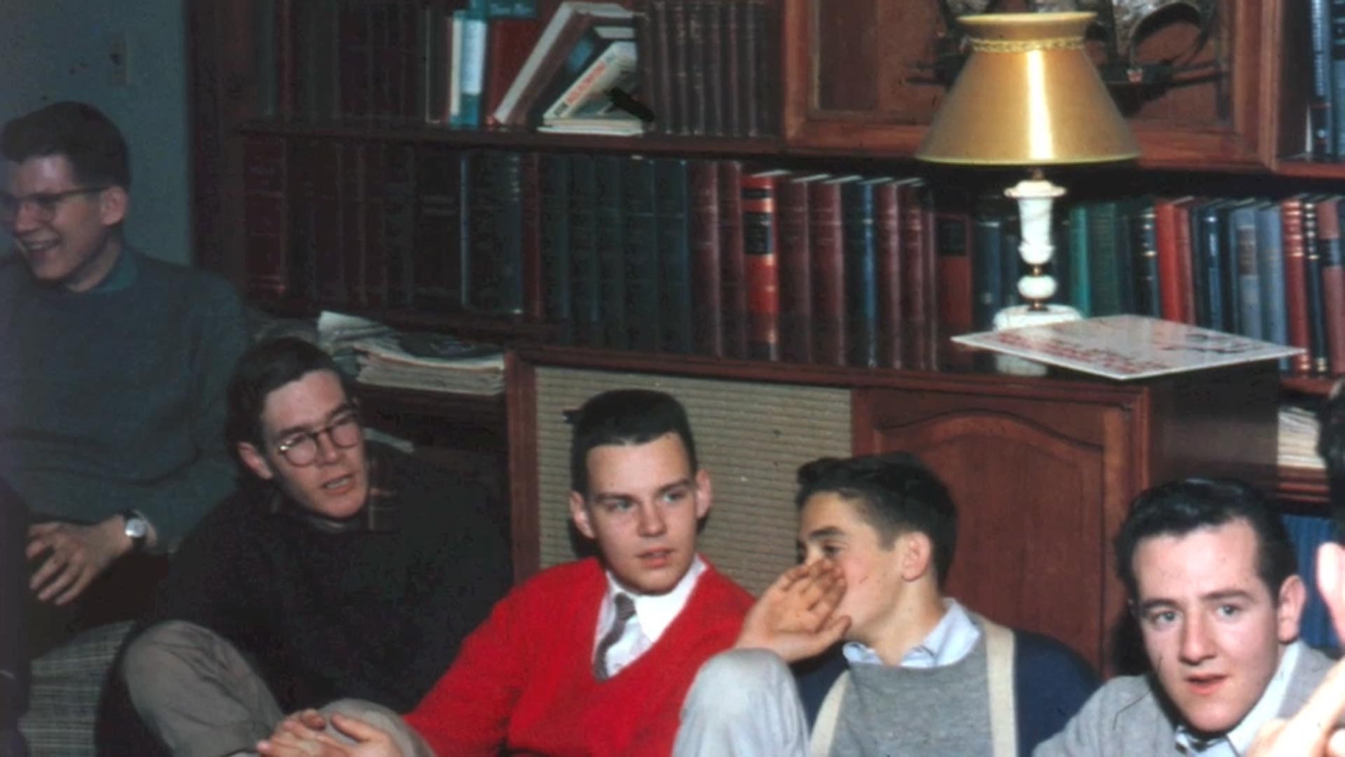 Young men studying together in library with bookshelves